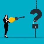 A lady holding a key shaped like a light bulb (idea) to fit the key of a question on a chain.