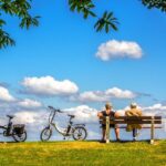 Two bicyclists resting on a park bench.