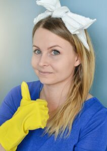 A cleaning person is smiling and doing a "thumbs up" with a yellow-gloved-hand.