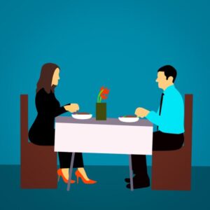 A couple on a date sitting across from one another at a dinner table. The attraction is obvious.