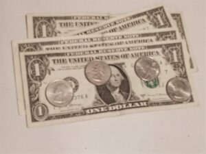 Close up of four quarters laid across a $1 bill. $1 = 4 quarters. An introduction to fractions using visual models.