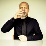 Businessman in a black shirt with a black tie drinking water.