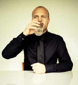 Businessman in a black shirt with a black tie drinking water.