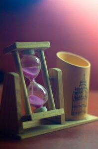Desktop hourglass with pencil cup. Large masted schooner is etched onto the pencil cup.