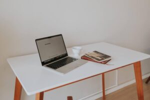 Minimalist desk with laptop and schoolbooks.