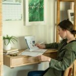 A girl in a green jacket practicing the Pomodoro method as she reviews her papers in her home office.