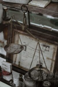 Antique weighing scale with coins, set in a vintage collection room, highlighting historical charm.