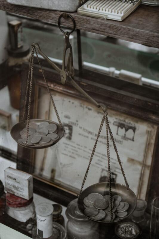 Antique weighing scale with coins, set in a vintage collection room, highlighting historical charm.