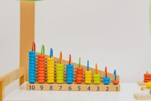 Multimodal learning tools including color-coded charts and physical manipulatives for student study. Close-up of a colorful wooden counting toy with numbers and shapes.