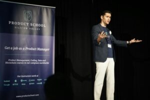 Confident presenter maintaining open body language and strong posture while speaking at a microphone.