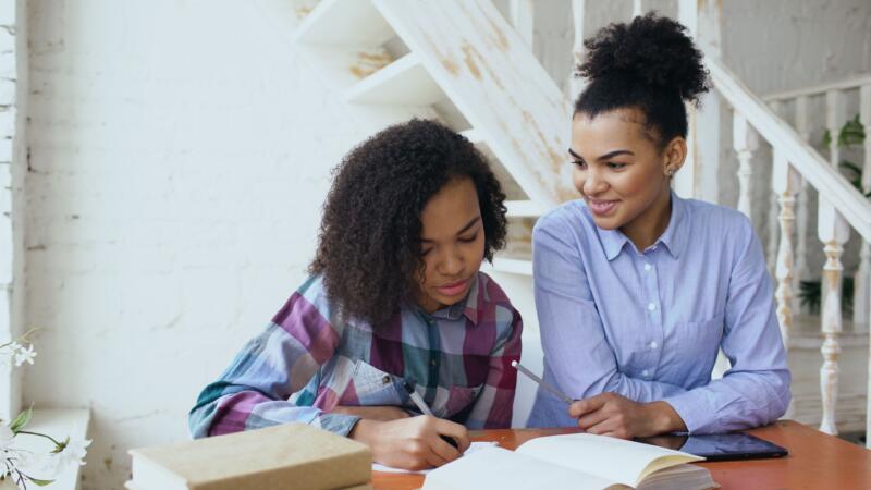 A mother encouraging her middle school daughter with math homework.