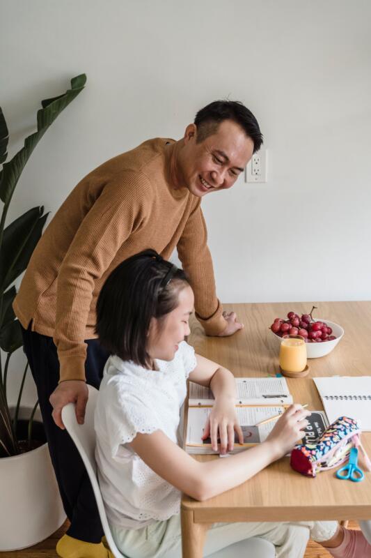 Parent supporting child with personalized study strategies at a clean desk workspace.