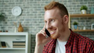 Professional smiling while speaking on a phone to project warm vocal tone over the phone.