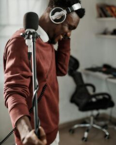 African male voice over artist recording a voice-over script with a condenser and Pioneer exclusive headphones.