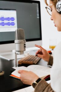 Voice actor speaking into a professional condenser microphone while reading an audiobook.