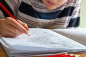 Student tracking math numbers and algebraic logic in a study notebook.