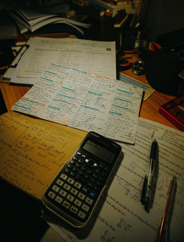 Student studying SAT math practice questions with graphing calculator and notes.