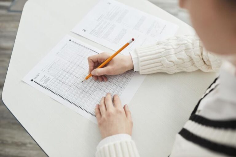 Close-up of a student filling out a multiple-choice exam in a quiet classroom setting.