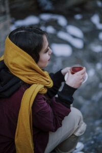 Person drinking warm honey tea for hoarse voice recovery and vocal strain relief.