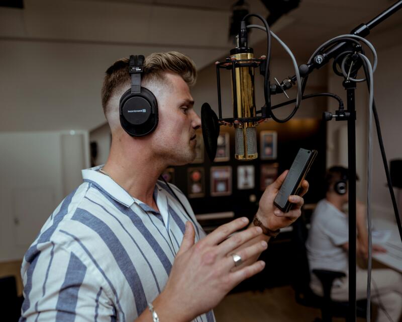 Voice actor recording character voices for audiobooks and animation in a soundproof studio microphone setup..