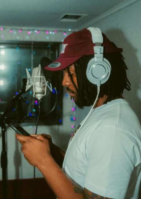 Voice actor wearing headphones holding a script at a studio recording microphone.