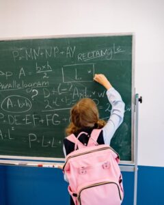 Student reaching up to write on a board illustrating physical height constraints.