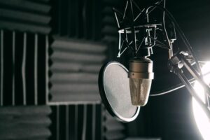 Studio condenser microphone with pop filter mounted in voiceover recording studio.