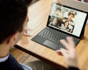 A person in a blue long-sleeve shirt making a presentation on Zoom and working on overcoming his fear of public speaking.