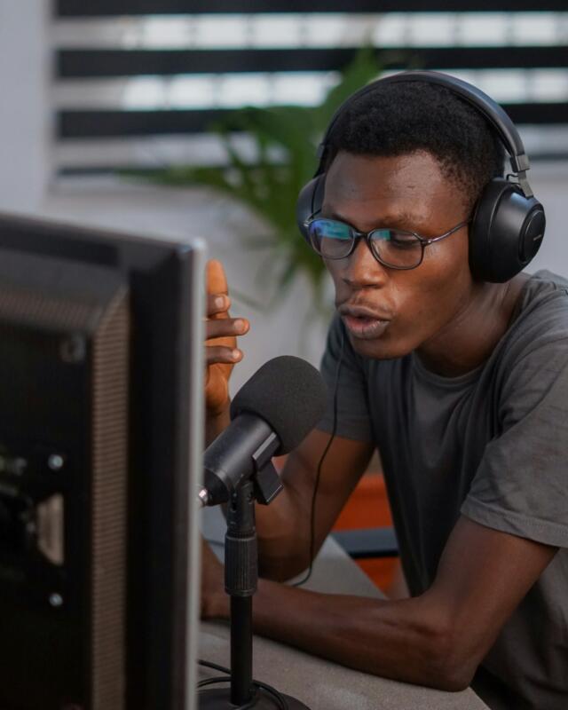 Adult student wearing headphones speaking into a microphone during an online speech coaching session.
