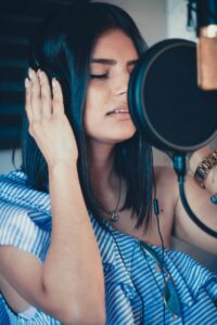 Voice student practicing vocal resonance exercises with microphone.