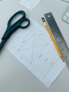 Top view of art supplies including scissors, pencil, and ruler on a white background.